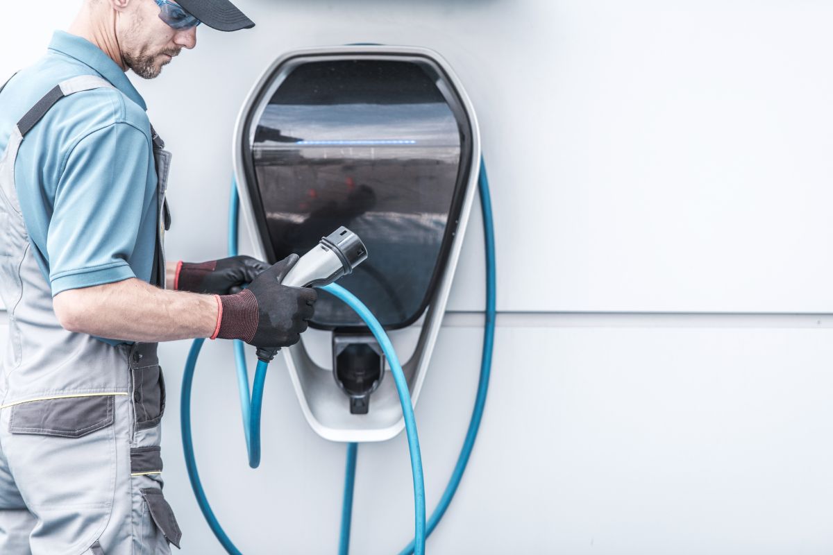 Pracownik montuje stację ładowania samochodów elektrycznych.