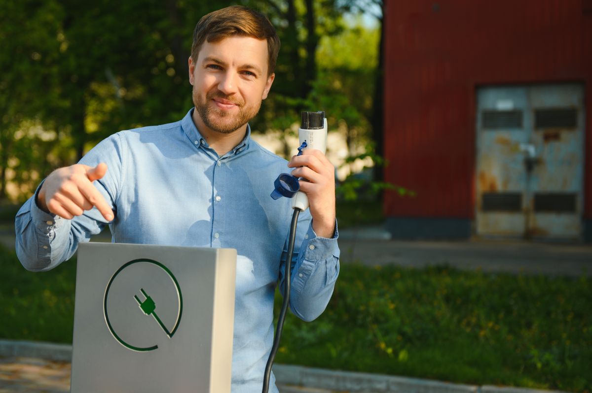 Mężczyzna wskazuje na punkt ładowania podczas instalacji stacji ładowania samochodów elektrycznych.