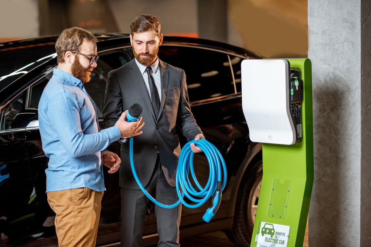Dwóch mężczyzn omawia instalację stacji ładowania samochodów elektrycznych.