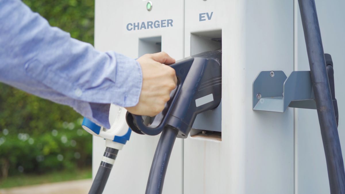 Ręka podłączająca kabel do stacji ładowania pojazdów elektrycznych.